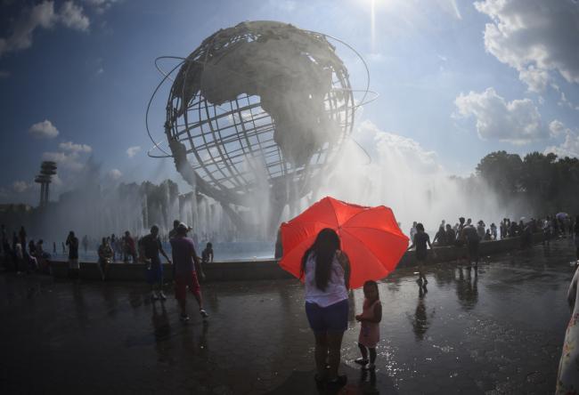 © Bloomberg. People cool off in the Unisphere fountain at Flushing Meadow Corona Park on July 21. 