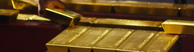 © Bloomberg. A worker lifts a gold bullion bar from a conveyor machine at the Rand Refinery Ltd. plant in Germiston, South Africa, on Wednesday, Aug. 16. 2017. Established by the Chamber of Mines of South Africa in 1920, Rand Refinery is the largest integrated single-site precious metals refining and smelting complex in the world, according to their website.