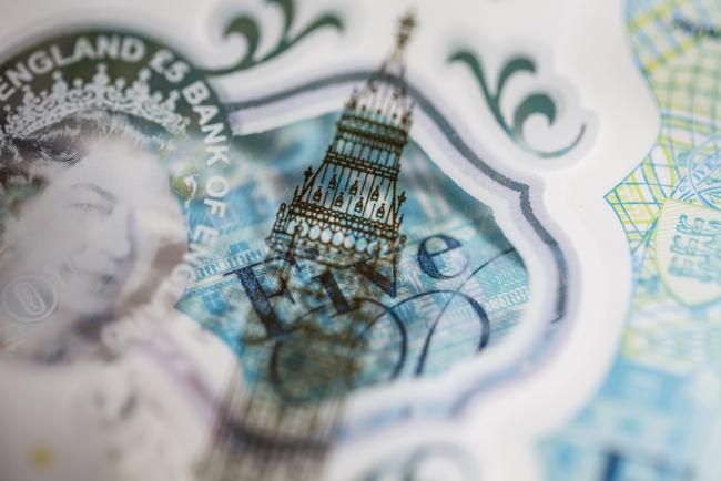 © Bloomberg. The Elizabeth Tower, also known as Big Ben, and a portrait of Queen Elizabeth II are seen on a British five pound banknote, in this arranged photograph in London, U.K.