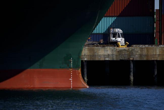 © Bloomberg. A truck drives past a container ship at the Port of Los Angeles in Los Angeles, California, U.S., on Wednesday, March 28, 2018. Long-only exchange-traded funds (ETFs) linked to broad baskets of energy, metals and agricultural products attracted $2.66 billion this quarter, Bloomberg Intelligence estimates show. While that's the largest quarterly inflow in data going back to 2005, the stream of money slowed in March as the U.S.-China trade row clouded the outlook for economic growth. 