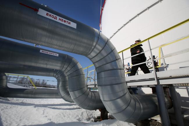 © Bloomberg. A worker passes oil pipes connecting an oil storage tank at a pumping station, operated by Rosneft PJSC, in the Samotlor oilfield near Nizhnevartovsk, Russia, on Monday, March 20, 2017. Russia's largest oil field, so far past its prime that it now pumps almost 20 times more water than crude, could be on the verge of gushing profits again for Rosneft PJSC. Photographer: Andrey Rudakov/Bloomberg