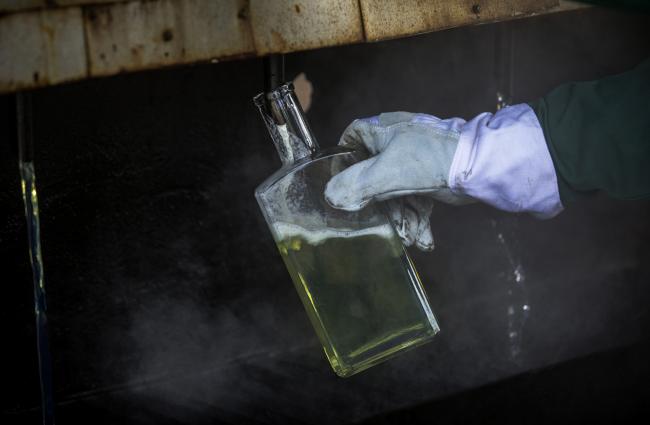 © Bloomberg. A worker collects a sample of light refined diesel fuel for quality control purposes at a testing facility in the Duna oil refinery.