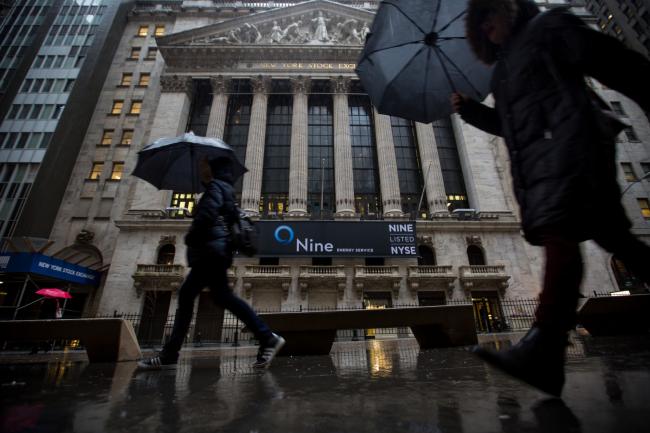 © Bloomberg. Pedestrians carrying umbrellas pass in front of the New York Stock Exchange (NYSE) in New York, U.S. Photographer: Michael Nagle/Bloomberg