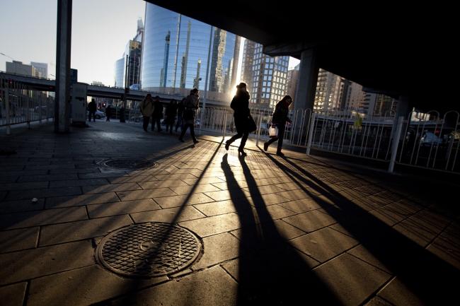 © Bloomberg. Commuters walk through the central business district in Beijing, China. 