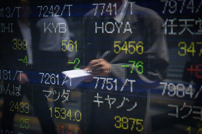 © Bloomberg. A man making notes is reflected in an electronic stock board outside a securities firm in Tokyo, Japan, on Friday, June 9, 2017.