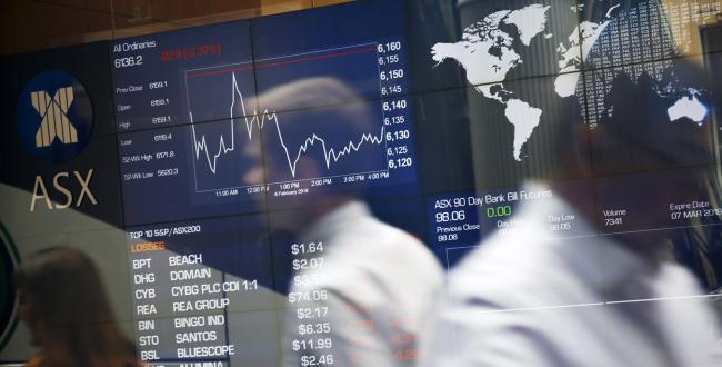 © Bloomberg. Pedestrians are reflected in a window as they walk past an electronic stock board at the ASX Ltd. exchange centre in Sydney, Australia. Photographer: David Moir/Bloomberg