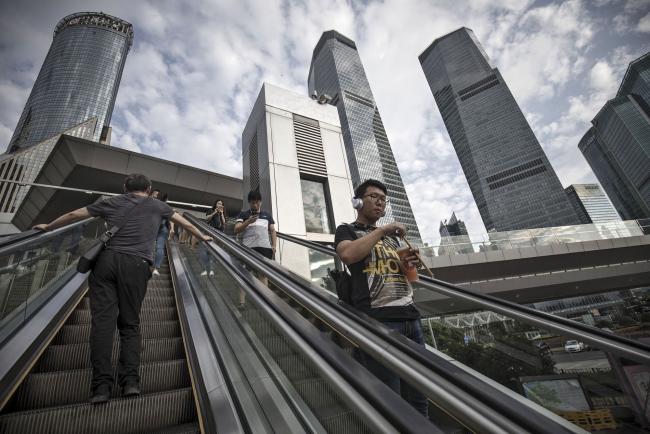 © Bloomberg. Pedestrians ride an escalator in the Lujiazui Financial District in Shanghai, China, on Monday, Sept. 4, 2017. The Chinese central bank's tight leash on liquidity is straining the bond market, with the benchmark sovereign yield climbing to near the highest level since April 2015. 
