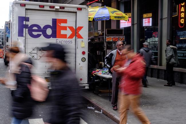 © Bloomberg. Pedestrians pass in front of a FedEx Corp. delivery truck parked on a street in New York, U.S., on Monday, Nov. 26, 2018. Photographer: Christopher Lee/Bloomberg