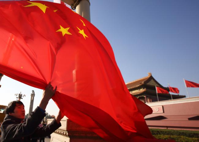 © Bloomberg. A worker lowers a Chinese national flag in front of Tiananmen Gate in Beijing, China, on Sunday, Nov. 9, 2014. President Xi Jinping signaled China is ready to accept a lower rate of growth, assuring executives that the economy is more resilient than ever and his government can safely guide the country through any slowdown. 