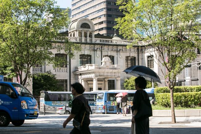 © Bloomberg. Pedestrians walk past the Bank of Korea (BOK) museum at the central bank's headquarters in Seoul, South Korea, on Thursday, Aug. 16, 2018. While the Bank of Korea has indicated that the next move in interest rates is likely to be upward and economists forecast one hike this year, the job market is making that an increasingly tough call. Photographer: Jean Chung/Bloomberg