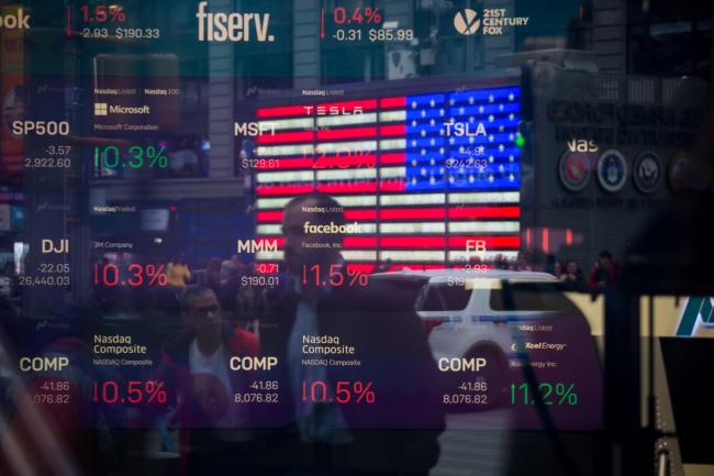 © Bloomberg. Monitors display stock market information as pedestrians are reflected in a window at the Nasdaq MarketSite in the Times Square area of New York, U.S., on Friday, April 26, 2019. U.S. stocks edged higher on better-than-forecast earnings while Treasury yields fell after data signaled tepid inflation in the first quarter. 