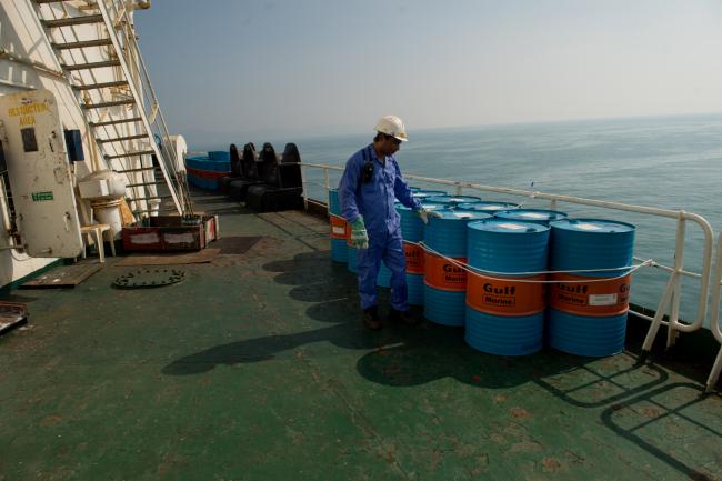 © Bloomberg. A crew man secures Gulf Marine oil drums on the deck of oil tanker 'Devon' as it prepares to transport crude oil from Kharq Island to India in Bandar Abbas, Iran.