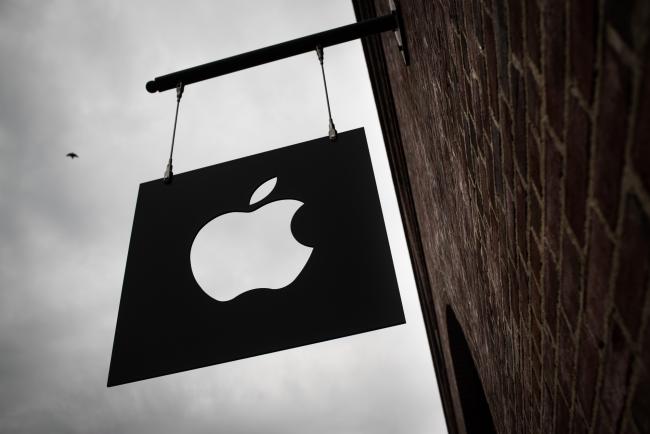 © Bloomberg. Apple Inc. signage hangs outside of the company's Williamsburg store in the Brooklyn borough of New York, U.S., on Friday, May 20, 2017. Apple Chief Executive Officer Tim Cook said in May that the company planned to invest at least $1 billion to back advanced manufacturing companies in the U.S. and help create jobs in the industry. 