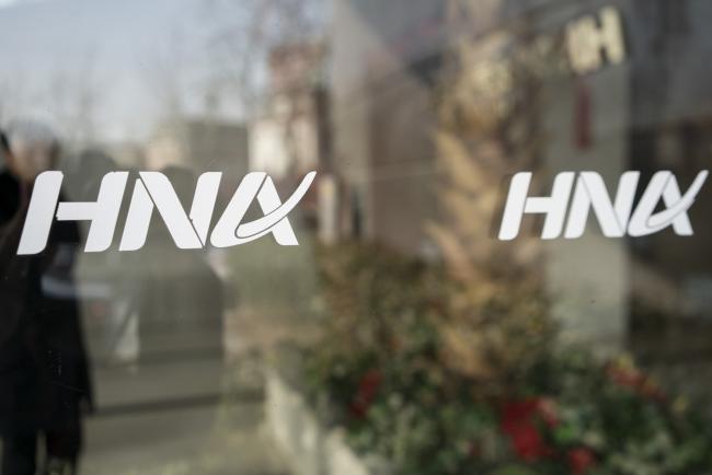© Bloomberg. Signage for HNA Group Co. is displayed on a pane of glass at the company's building in Beijing, China, on Thursday, Feb. 1, 2018. Companies linked to HNA Group Co. have secured 7.8 billion yuan ($1.2 billion) in long-term loans from Chinese banks to finance an expansion project in Meilan Airport in HNA’s home province of Hainan. 