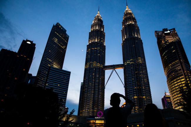 © Bloomberg. The Petronas Twin Towers, center, stand in Kuala Lumpur, Malaysia, on Friday, May 18, 2018. Malaysian Prime Minister Mahathir Mohamad's government is considering investigating former leader Najib Razak for abuse of power, as it intensifies efforts to seek evidence of wrongdoing at scandal-plagued state fund 1MDB just days after taking office. 