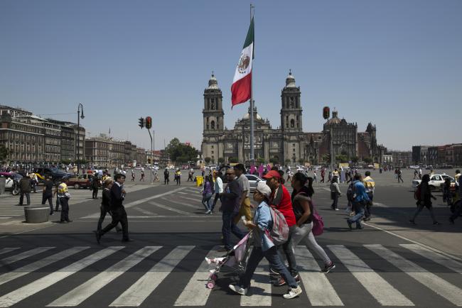 © Bloomberg. People walk outside the Metropolitan Cathedral in the Zocalo neighborhood of Mexico City, Mexico, on Tuesday, March 15, 2016.