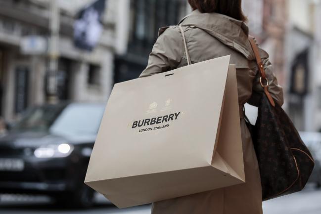 © Bloomberg. A shopper carries a Burberry Group Plc branded shopping bag in London, U.K., on Monday, Oct. 15, 2018. Gianni Versace SpA’s sale to Michael Kors Holdings Ltd. leaves a dwindling number of independent global fashion brands still up for grabs. Photographer: Jason Alden/Bloomberg