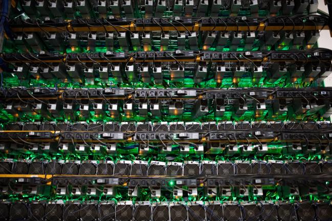 © Bloomberg. Cryptocurrency mining rigs sit on racks at a Bitfarms facility in Saint-Hyacinthe, Quebec, Canada. Photographer: James MacDonald/Bloomberg
