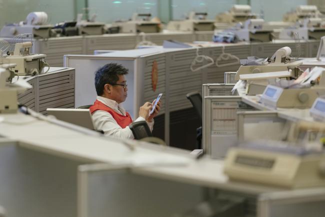 © Bloomberg. A trader uses a smartphone on the trading floor of the Hong Kong Stock Exchange, operated by Hong Kong Exchanges & Clearing Ltd. (HKEX), in Hong Kong, China, on Tuesday, Oct. 24, 2017.