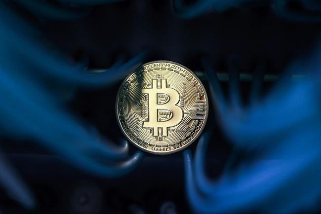 © Bloomberg. A bitcoin sits among an Ethernet cables inside a communications room at an office in this arranged photograph in London, U.K. Photographer: Chris Ratcliffe/Bloomberg