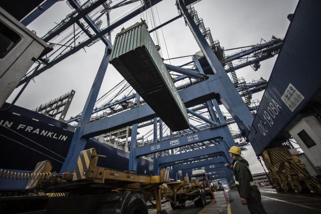 © Bloomberg. A dock worker directs the loading of shipping containers onto CMA CGM SA's Benjamin Franklin container ship docked at the Guangzhou Nansha Container Port in Guangzhou, China. Photographer: Qilai Shen