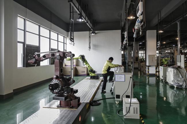 © Bloomberg. A technician climbs a set of step ladders next to industrial robots on the testing line of a factory operated by E-Deodar Robot Equipment Co., a wholly-owned subsidiary of Ningbo Techmation Co., in Foshan, China, on Tuesday, Feb. 28, 2017. Startup E-Deodar is building $15,000 industrial bots that are about a third cheaper than foreign brands and are being used to automate assembly lines across the Pearl River Delta manufacturing hub. China is embracing robotics with the same full-on intensity that's made it a force in high-speed rail and renewable energy.