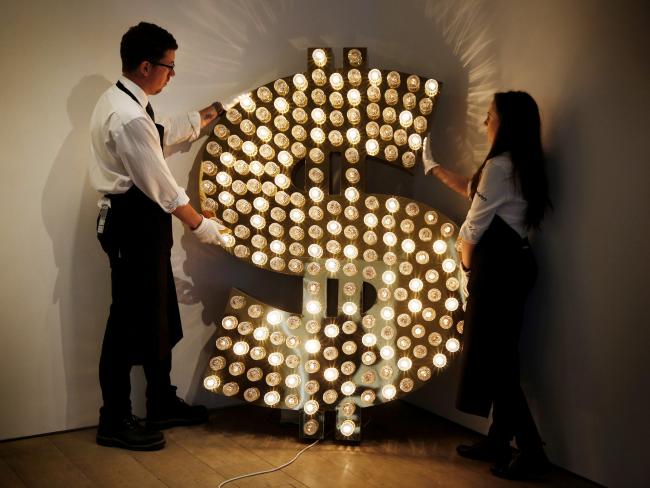 © Bloomberg. Sotheby's employees pose with a piece of artwork entitled 