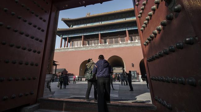 © Bloomberg. Visitors walk through a gate inside the Palace Museum at the Forbidden City in Beijing,