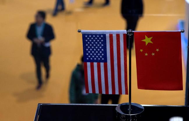 © Bloomberg. Chinese and US flag at a booth during the first China International Import Expo (CIIE) in Shanghai. 