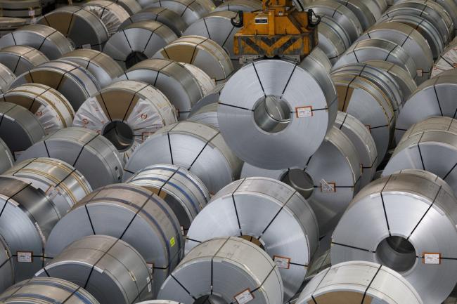 &copy Bloomberg. A crane maneuvers a roll of steel above a storage area ahead of shipping, in Germany.