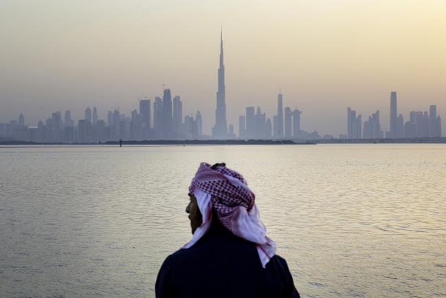 © Bloomberg. An Emirati man looks out from the Dubai Creek Habour Development towards the Burj Khalifa tower, center, and other skyscrapers in Dubai, United Arab Emirates, on Monday, June 18, 2018.  Photographer: Christopher Pike/Bloomberg