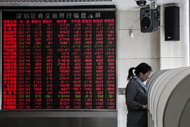 © Bloomberg. A woman stands at a trading terminal near an electronic board displaying share prices at a securities brokerage in Beijing, China, on Monday, March 7, 2016. Chinese small-cap stocks rallied after Premier Li Keqiang failed to mention a planned shift to a more market-based system for initial public offerings, a reform seen luring funds from existing equities. Photographer: Qilai Shen/Bloomberg