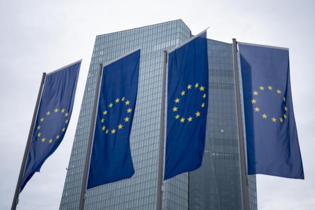 © Bloomberg. The stars of the European Union (EU) sit on banners flying outside the European Central Bank (ECB) headquarters ahead of the central bank's interest rate decision news conference in Frankfurt, Germany, on Thursday, Sept. 13, 2018. The ECB confirmed it will cut bond-buying in half next month and anticipates that new purchases will be halted by the end of the year. Photographer: Jasper Juinen/Bloomberg