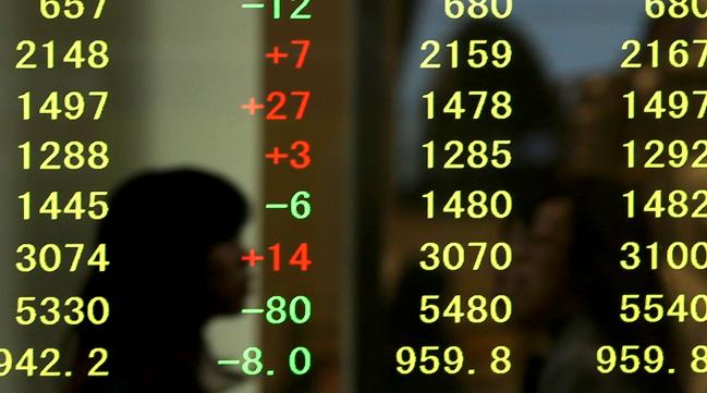 © Bloomberg. A pedestrian is reflected in an electronic stock board outside a securities firm in Kobe, Hyogo Prefecture, Japan. Photographer: Buddhika Weerasinghe/Bloomberg