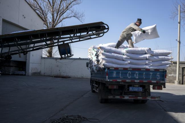© Bloomberg. A worker loads sacks of hog feed onto a truck at the Tianjin Tianjiao Group feed mill in Tianjin, China, on Friday, Feb. 2, 2018.