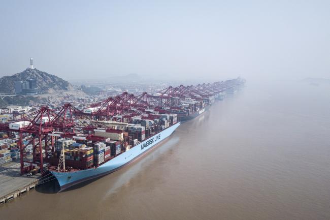© Bloomberg. An A.P. Moller-Maersk A/S container ship and a Hapag-Lloyd AG container ship are docked as shipping containers stand in a terminal at the Yangshan Deep Water Port in this aerial photograph taken in Shanghai, China, on Friday, March 23, 2018. 