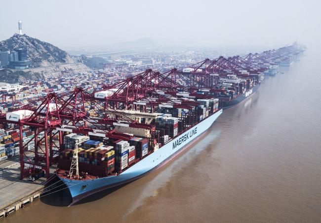© Bloomberg. An A.P. Moller-Maersk A/S container ship and a Hapag-Lloyd AG container ship are docked as shipping containers stand in a terminal at the Yangshan Deep Water Port in this aerial photograph taken in Shanghai, China, on Friday, March 23, 2018. The trade conflict between China and the U.S. escalated, with Beijing announcing its first retaliation against metals levies hours after President Donald Trump outlined fresh tariffs on $50 billion of Chinese imports and pledged there's more on the way. 