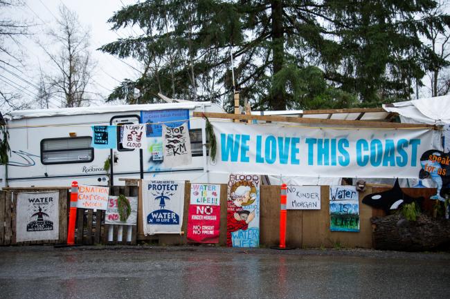 © Bloomberg. Protest signs are displayed outside of the Kinder Morgan Inc. facility in Burnaby, British Columbia, Canada, on , April 11.