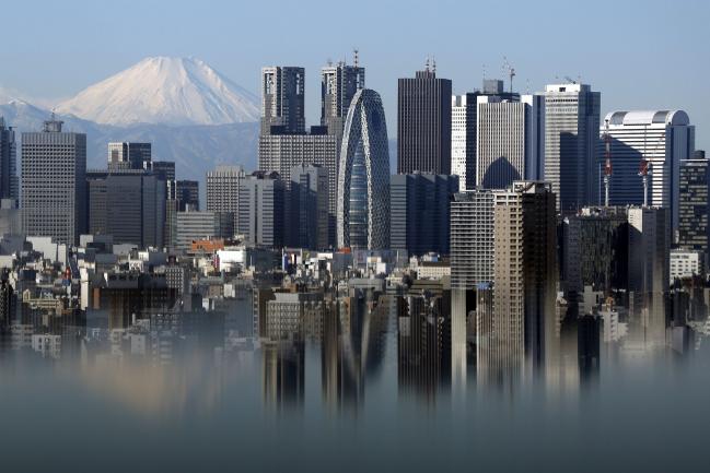 © Bloomberg. Mount Fuji and buildings in the Shinjuku district are reflected on a table at an observation deck in Tokyo, Japan.