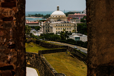 © Bloomberg. The Capitol Building is seen past walls in the Old City of San Juan, Puerto Rico, on Wednesday, July 8, 2015. Photographer: Bloomberg/Bloomberg