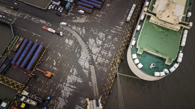 © Bloomberg. A Tesla Inc. Model 3 electric vehicle, center, travels through a port after being driven off the Morning Cindy vehicle carrier in this aerial photograph taken in Shanghai, China, on Friday, Feb. 22, 2019. Tesla Model 3s began rolling off a ship at Shanghai's port today as the automaker rushes to get cars to the worlds largest electric vehicle market before the deadline of a trade-war truce between China and U.S. expires. 