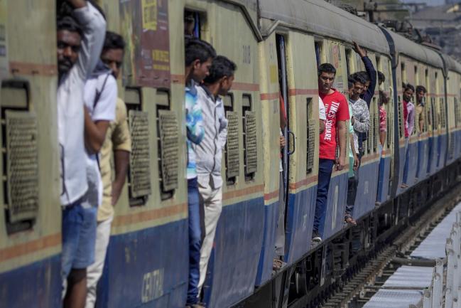 © Bloomberg. Passengers stand in the doorways of train carriages as the train arrives at Sandhurst Road railway station in Mumbai, India, on Saturday, Jan. 27, 2018. Mumbai's suburban railway, the oldest in Asia, is one of the busiest for commuters in the world and with 8 million daily rail travelers it's also one of the most crowded. Trains have been chugging up its Central line — between what's now the World Heritage listed Chhatrapati Shivaji Maharaj Terminus in the city's south and Thane, 34 kilometers (21 miles) north — since 1853. Photographer: Dhiraj Singh/Bloomberg