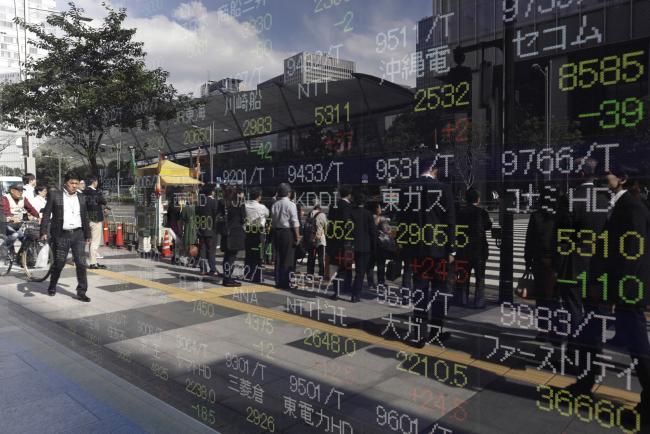 © Bloomberg. Pedestrians are reflected in an electronic stock board outside a securities firm in Tokyo, Japan, on Wednesday, Oct. 18, 2017. 