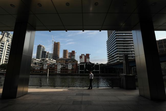 © Bloomberg. A worker stands near the water's edge at the Canary Wharf business, financial and shopping district in London, U.K., on Thursday, June 5, 2018. The owners of a Canary Wharf skyscraper leased to Citigroup Inc. are seeking to refinance the 661 million-pound ($882 million) loan used to buy it five years ago, two people with knowledge of the plan said. Photographer: Chris Ratcliffe/Bloomberg