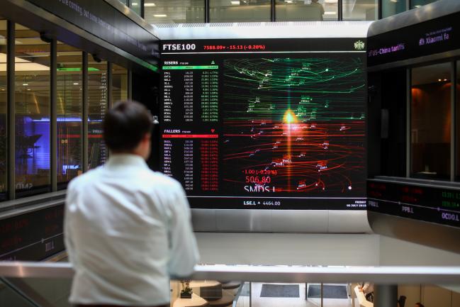 © Bloomberg. An employee looks at a screen displaying FTSE 100 share price information in the atrium of the London Stock Exchange Group Plc's offices in London. Photographer: Simon Dawson/Bloomberg