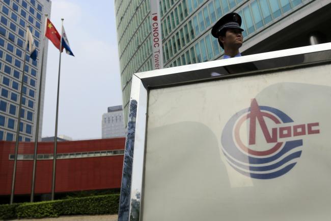 © Bloomberg. The Chinese national flag flies near a security guard outside the Cnooc Ltd. headquarters in Beijing, China.