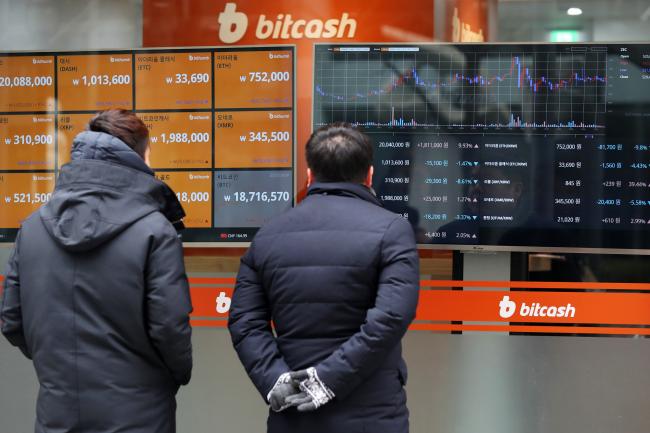 © Bloomberg. Pedestrian look at monitor showing the prices of virtual currencies at the Bithumb exchange office in Seoul, South Korea, on Friday, Dec. 15, 2017.