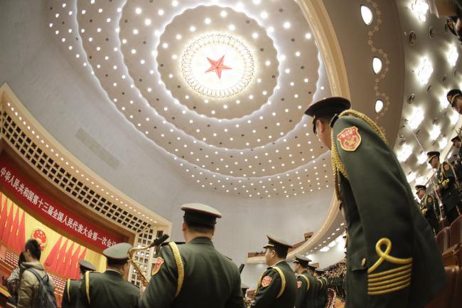 © Bloomberg. Members of the Chinese People's Liberation Army (PLA) band stand ahead of the opening of the first session of the 13th National People's Congress (NPC) at the Great Hall of the People in Beijing, China, on Monday, March 5, 2018. China set a 2018 growth target of around 6.5 percent, omitting an intention to hit a faster pace if possible, as leaders intensify their push to ensure financial stability.