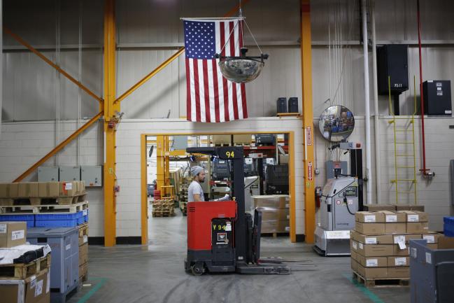 © Bloomberg. An American flag hangs above a worker operating a forklift at the Stihl Inc. manufacturing facility in Virginia Beach, Virginia, U.S., on Thursday, Jan. 11, 2018. The Federal Reserve is scheduled to release industrial production figures on January 17. Photographer: Luke Sharrett/Bloomberg