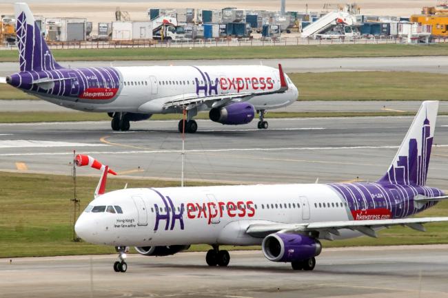 © Bloomberg. A Hong Kong Express Airways Ltd. aircraft taxis past another aircraft operated by the airline at Hong Kong International Airport in Hong Kong, China, on Tuesday, March 5, 2019. Cathay Pacific Airways Ltd. is in talks to buy shares in Hong Kong’s only budget airline Hong Kong Express from Chinese conglomerate HNA Group Co., as Asia’s biggest international carrier seeks to gain a foothold in the region’s booming low-cost travel market. Photographer: Paul Yeung/Bloomberg